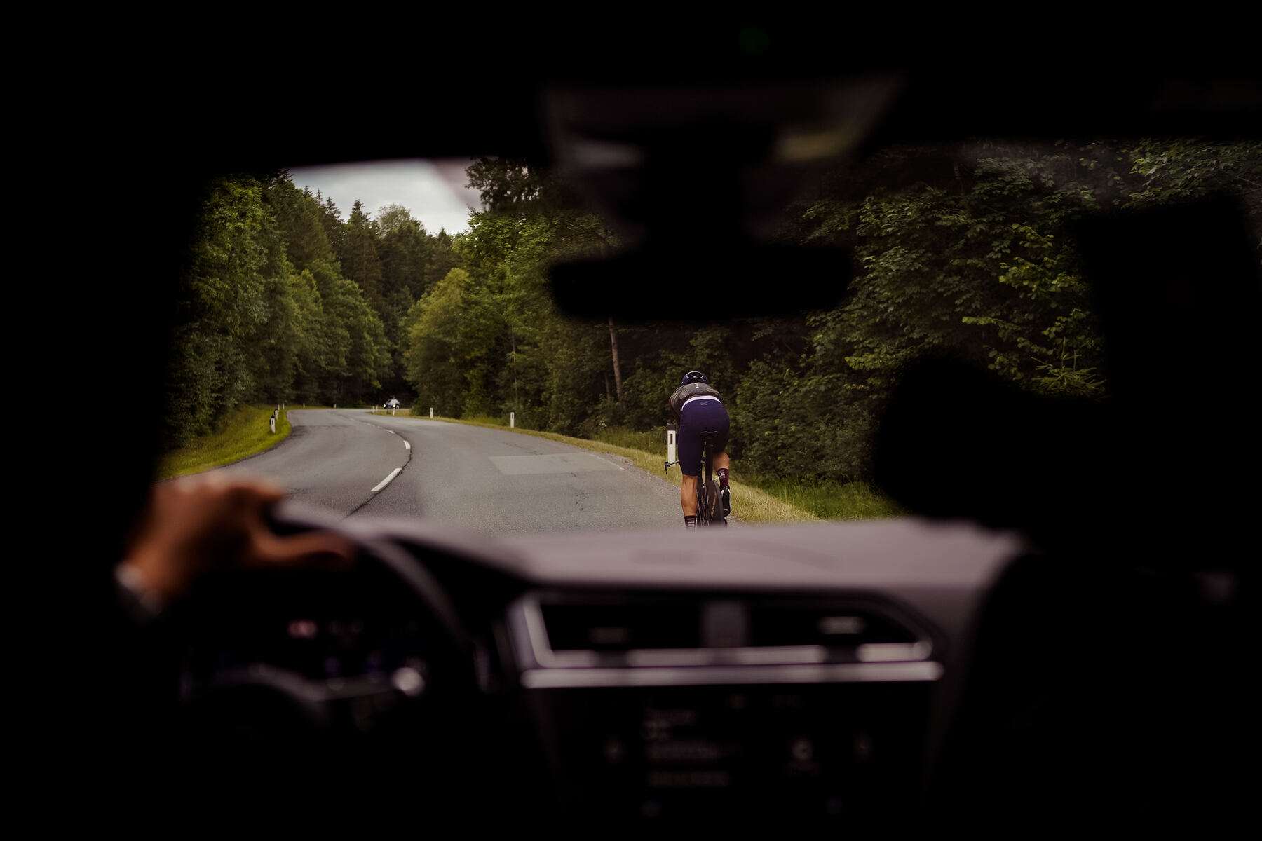 Blick aus dem Begleitfahrzeug auf einen Radfahrer auf der Landstraße