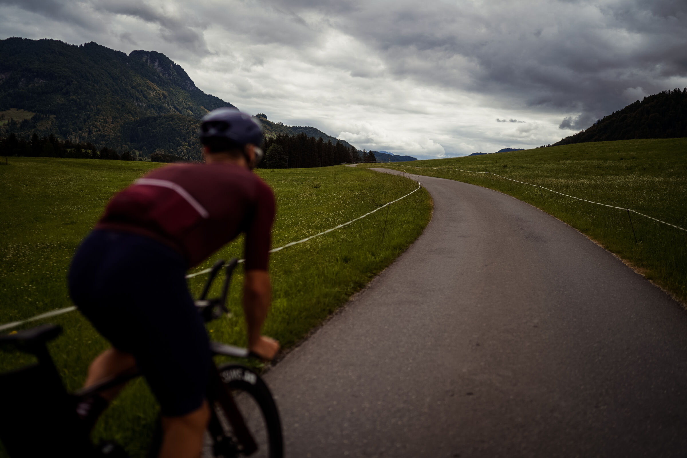 Radfahrer auf einer einsamen Straße vor Bergkulisse